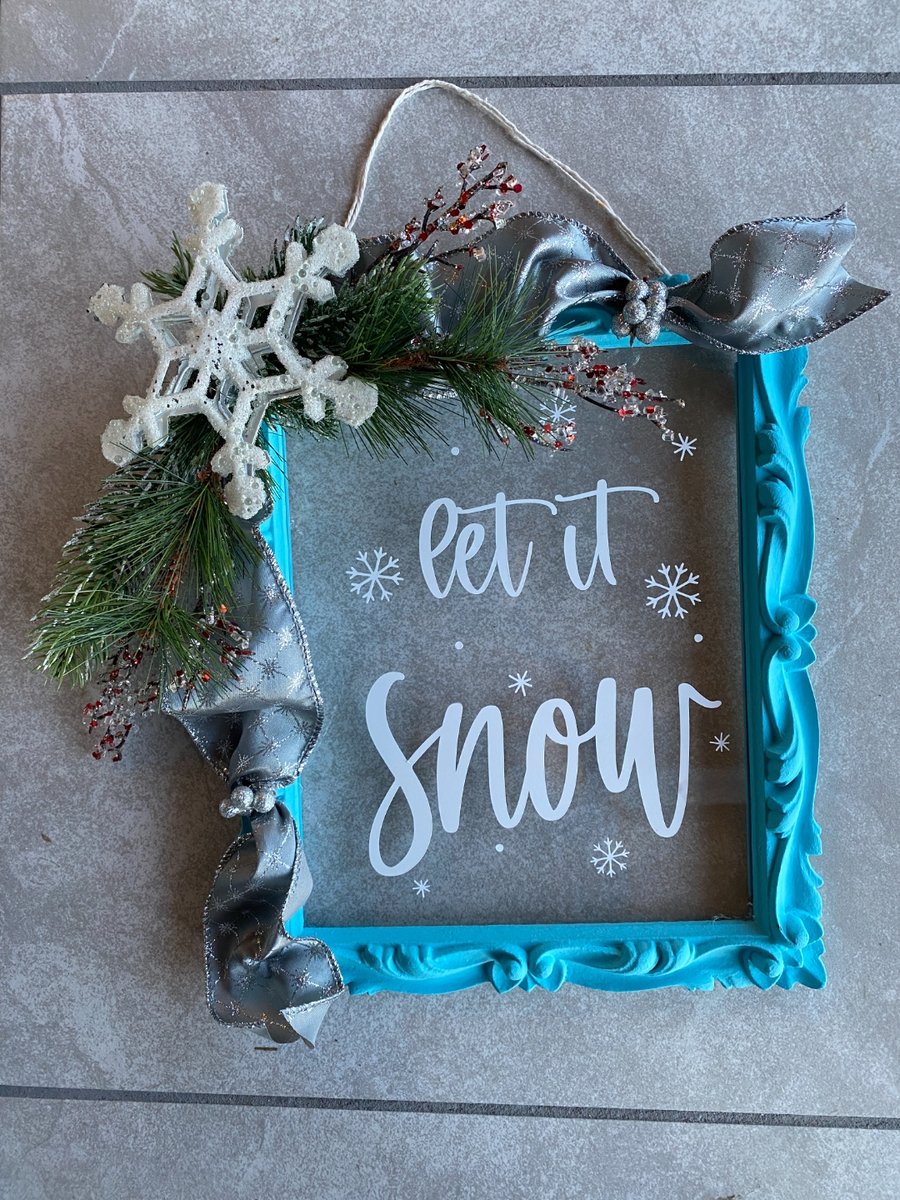Turquoise ornate picture frame painted and decorated with a 'Let It Snow' vinyl sign, winter pine sprigs, glitter snowflake, and silver bow