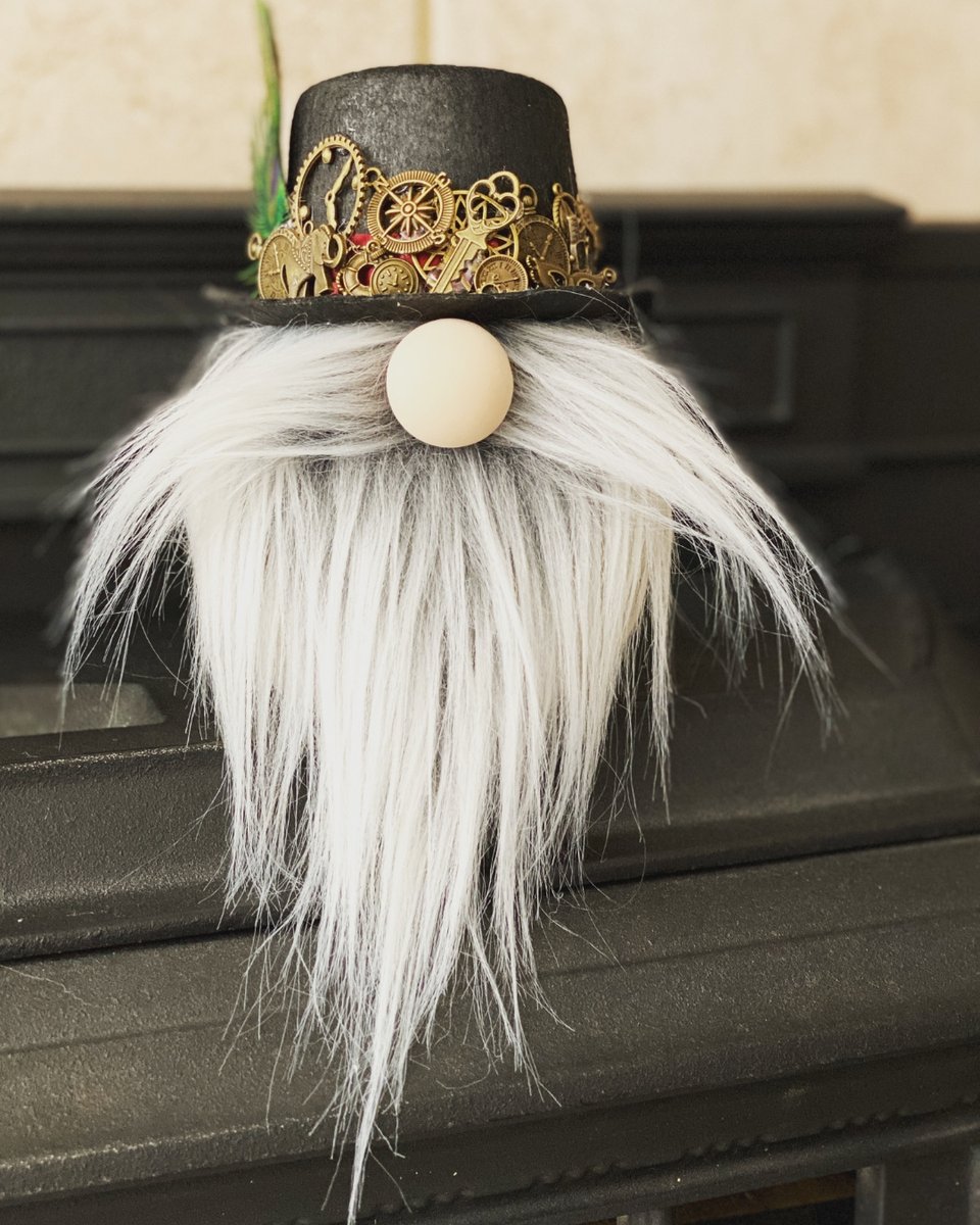 Handcrafted steampunk gnome with a black top hat decorated with brass gears and keys, and a long flowing white beard