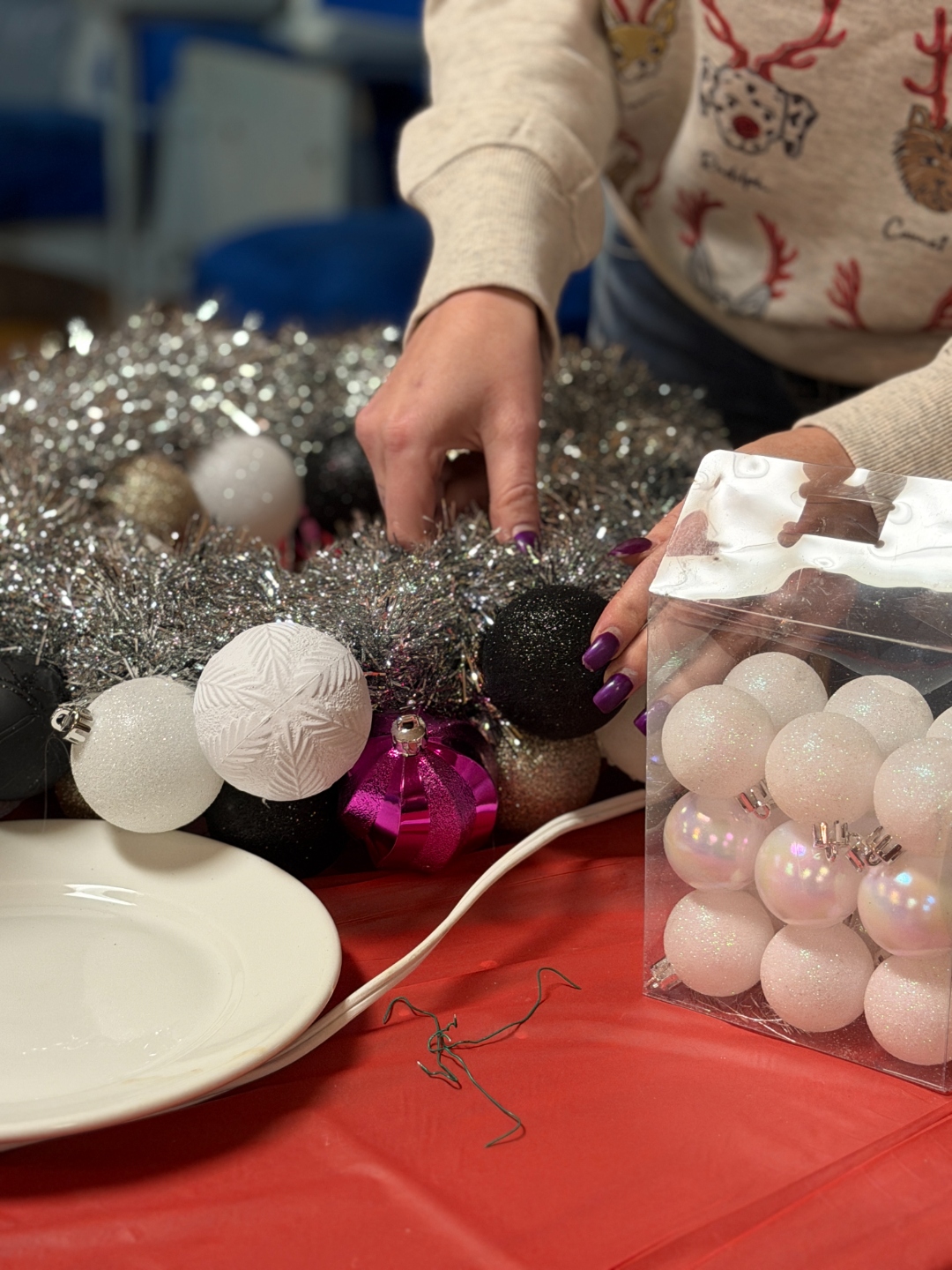 Hands arranging ornaments to create a holiday wreath at a Cricket Creek Studio workshop